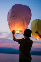 A cozy illustration of a child holding a glowing lantern on a forest path at twilight