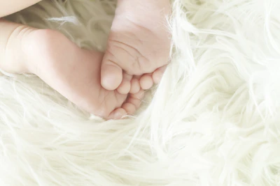 A child’s small feet snug in soft cotton slippers, standing on a fluffy white rug.