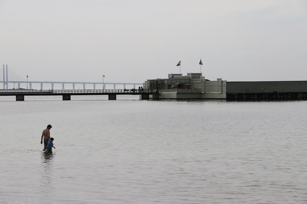 man holding child while standing in body of water