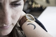 Minimalist tattoo of a small crescent moon on the wrist.