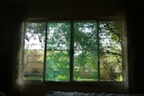 The room’s picturesque window with curtains drawn back, revealing greenery outside.