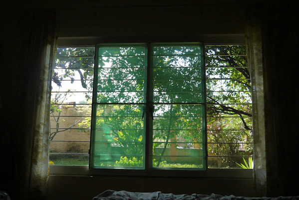 Soft olive green curtains gently flowing in natural light, framing a window with a view of greenery.
