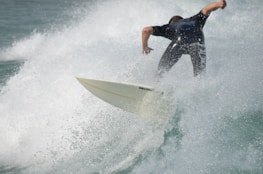A surfer riding a wave with water splashing around. The person is wearing a wetsuit and appears to be skillfully navigating the surfboard through the dynamic movement of the waves.