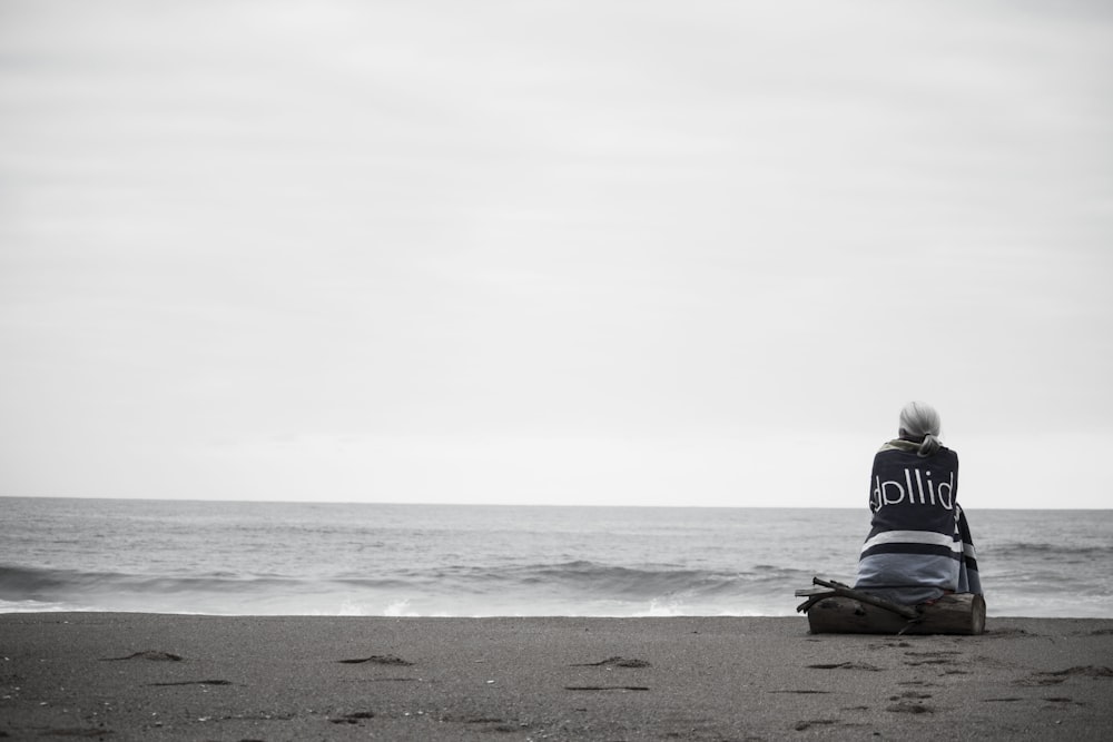 mulher sentada perto da costa durante o dia