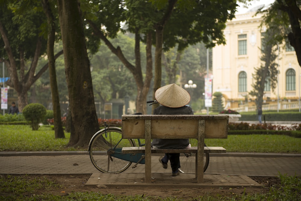 Persona sentada en un banco frente a una bicicleta de cercanías