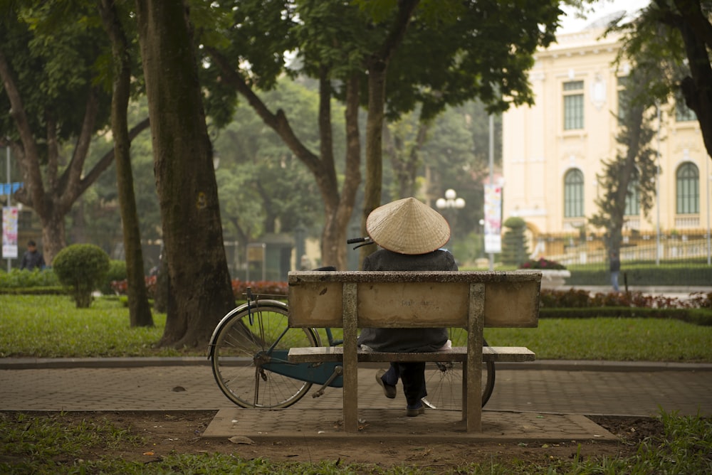 person sitting on bench in front of commuter bike