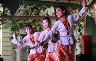 Women in colorful traditional dresses performing a folk dance at a cultural festival.