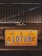 A close-up of a vehicle's front grill with a prominent yellow and blue license plate from Grand Bahama. The license plate has the number 10768 and includes the years 1492 and 1992 with emblems on either side.