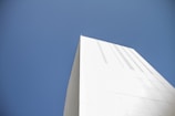 Minimalist white building with sharp lines under a clear blue sky.