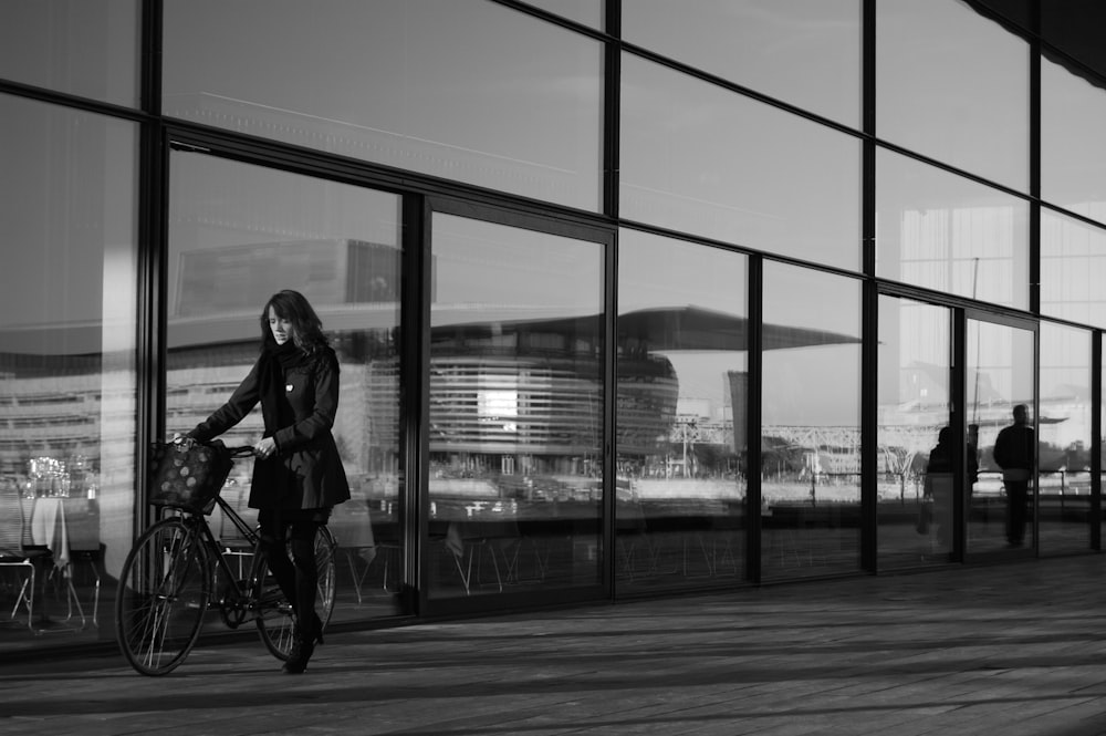 Photographie en niveaux de gris d’une femme tenant un vélo