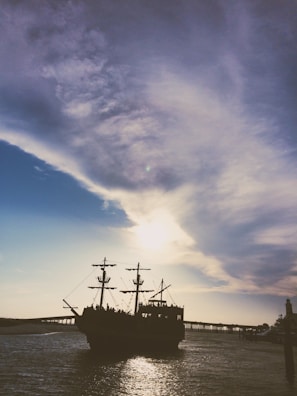 A sleek pirate ship sailing under a sunset sky, symbolizing bold ventures.