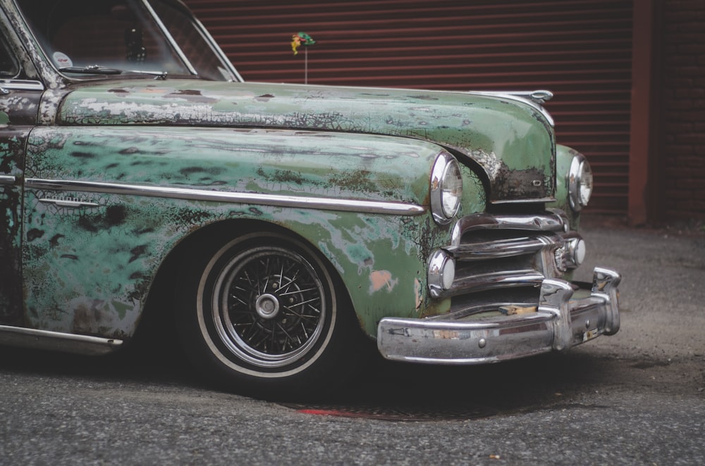 close-up photo of classic green car parked near building