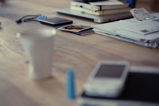 A stack of colorful ebooks on a wooden desk with a laptop and coffee cup.