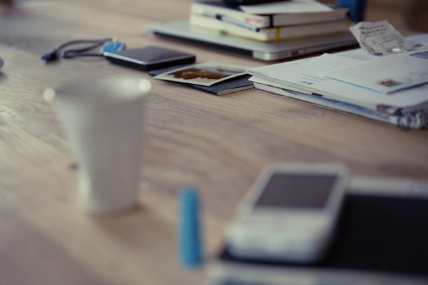 A stack of colorful ebooks on a wooden desk with a laptop and coffee cup.