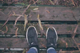 A pair of sleek black rubber shoes resting on a wooden bench in a park.