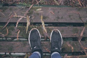 A pair of sleek black rubber shoes resting on a wooden bench in a park.