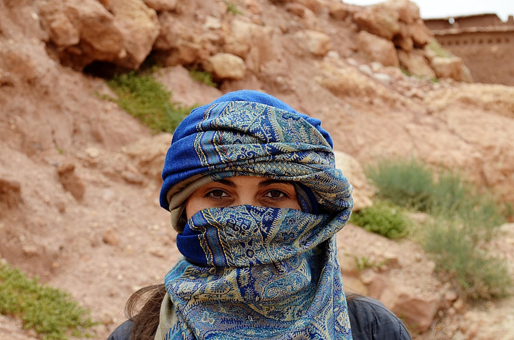 Femme masquée debout à côté du rocher
