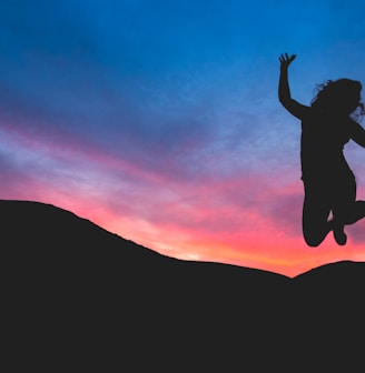 silhouette of person jumping during dawn