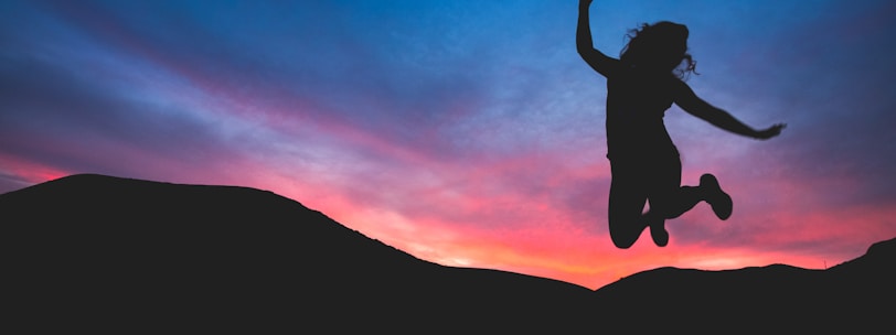 silhouette of person jumping during dawn