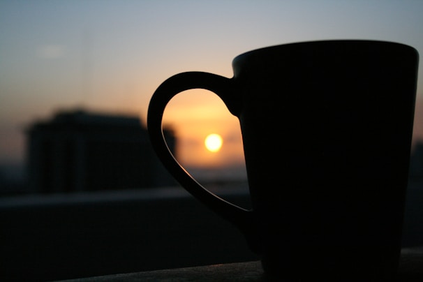 A colorful mug showing a sunset scene with warm oranges and deep purples.