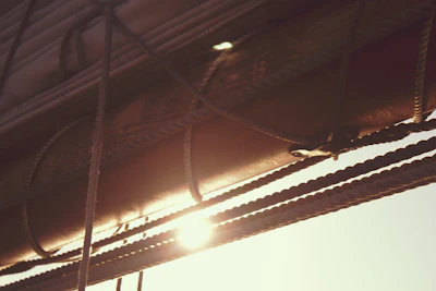 Close-up of ropes and sails in soft focus, sunlight casting warm shadows on deck.