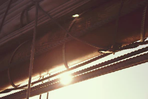 Close-up of ropes and sails softly blurred, bathed in the rich terracotta hues of dusk.