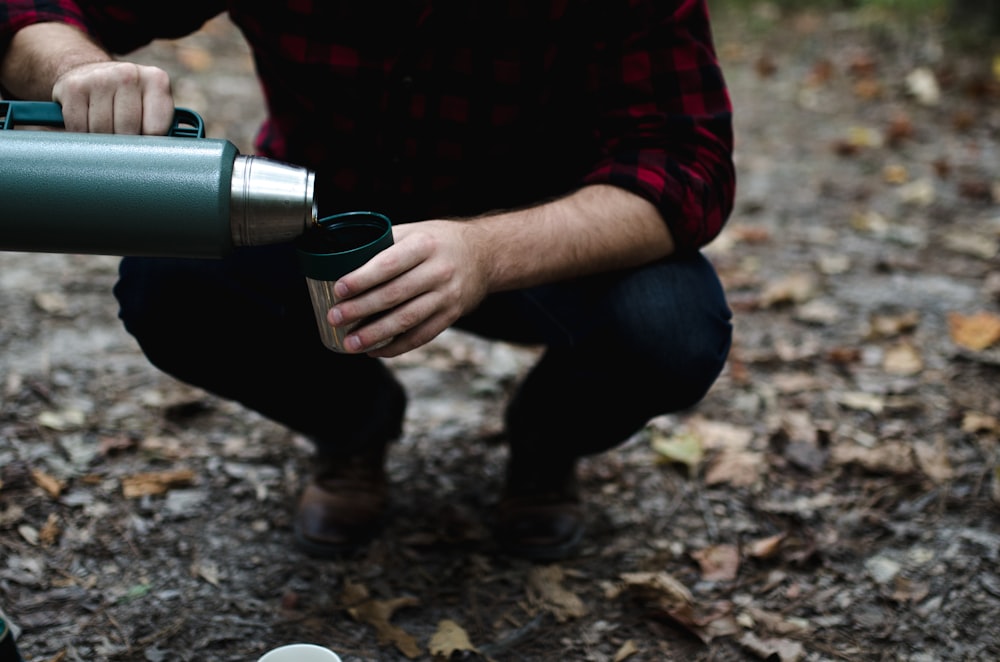 man bending his knees pouring thermal carafe in cup