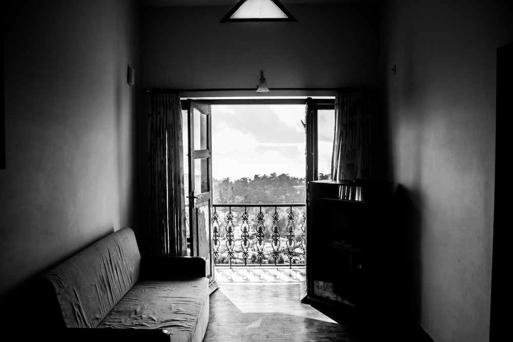 greyscale photgraphy of fabric sofa beside wall inside the building