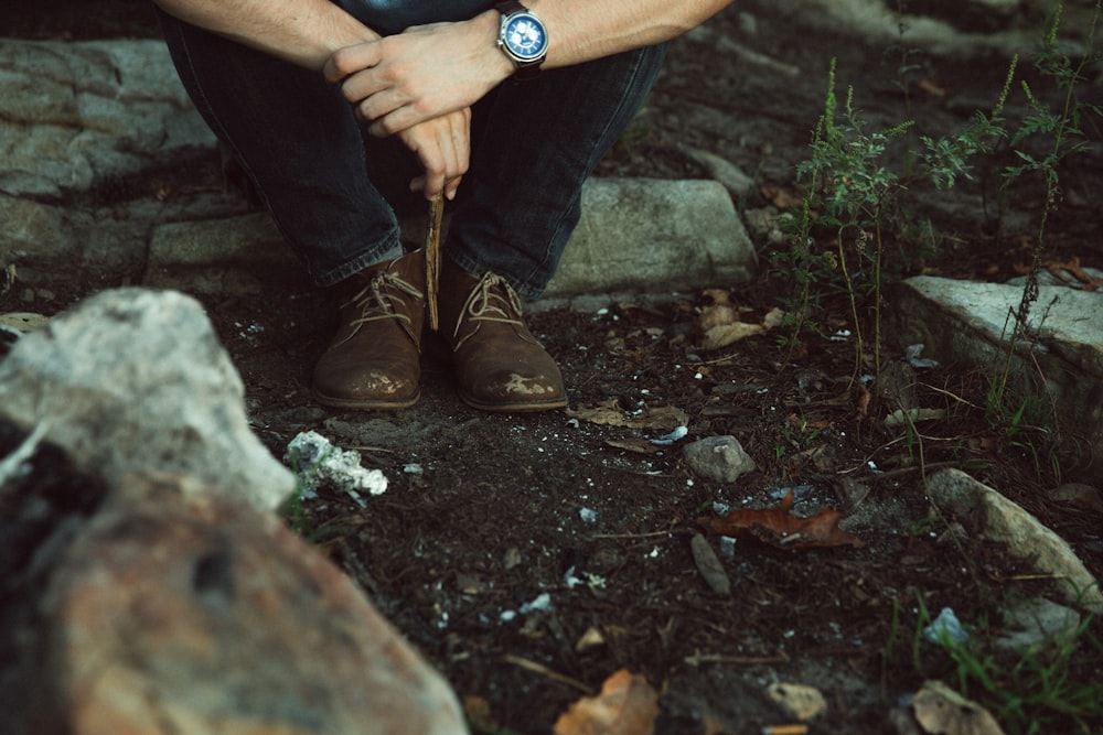 man sitting on gray rock during daytime