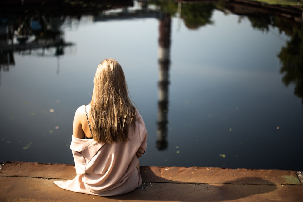 woman sitting down on porch beside body of water