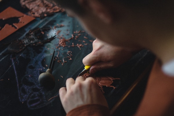Person carving on a dark wood plank in a workshop