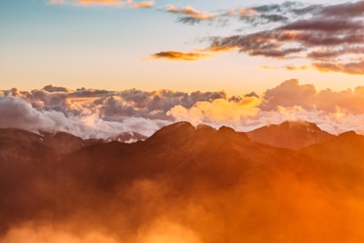 mountain peaks rising from the clouds during golden hour