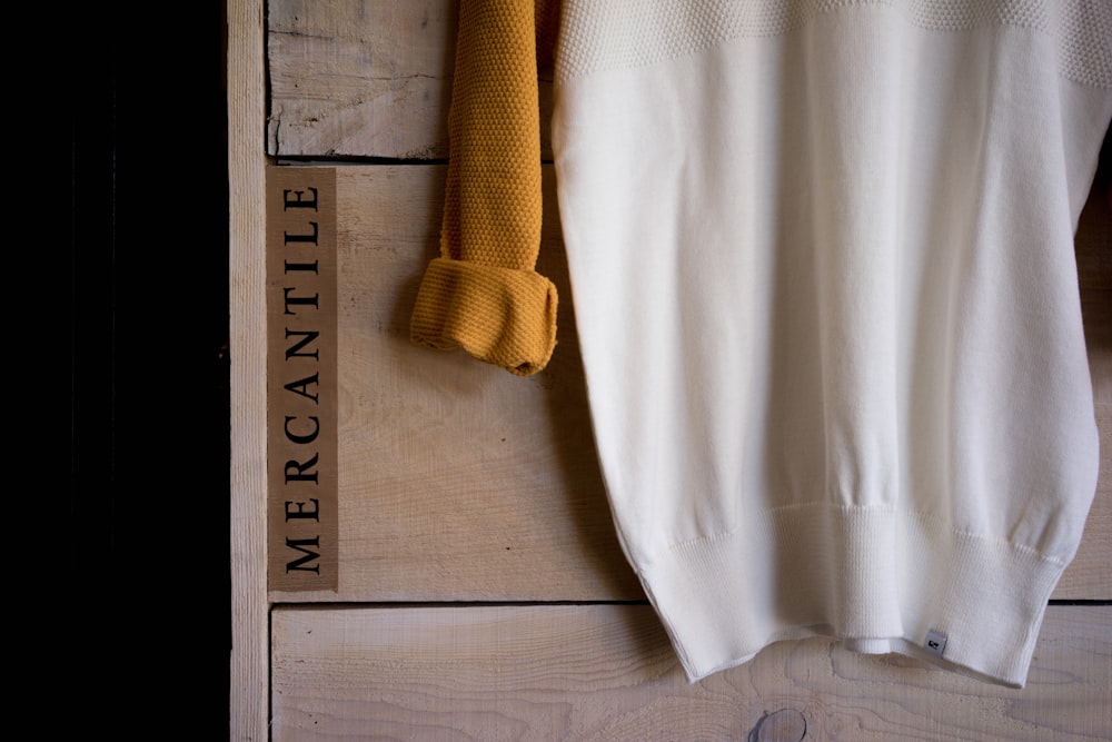 a white sweater hanging on a wooden wall