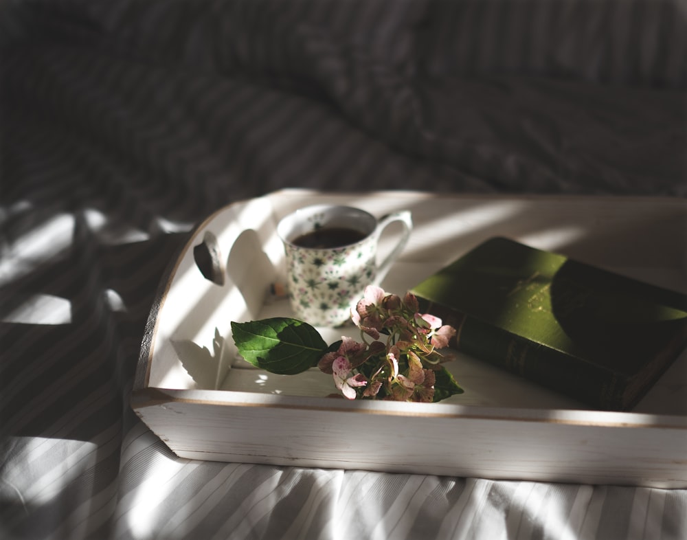 taza de té junto a flores rosas en bandeja
