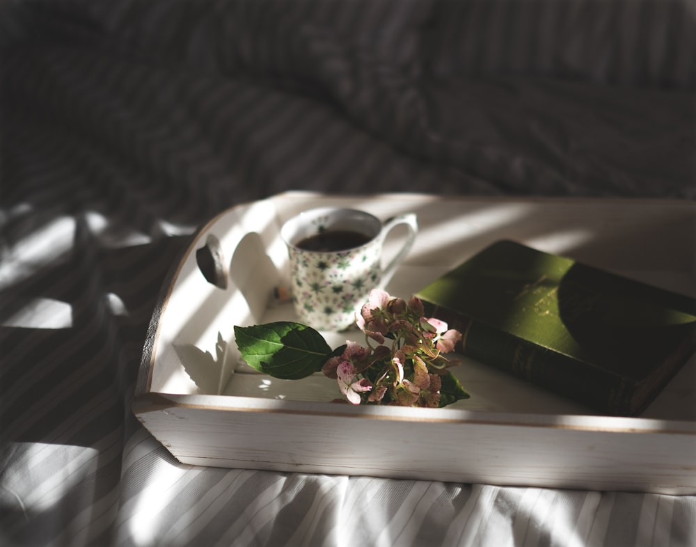 tazza da tè accanto a fiori rosa sul vassoio