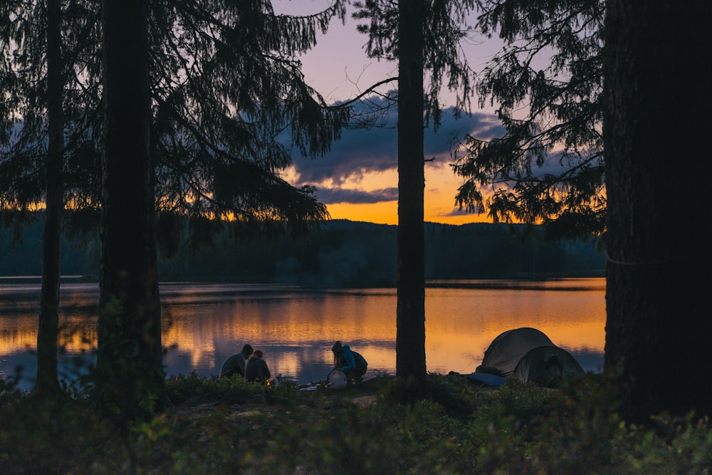 people beside body of water at golden hour