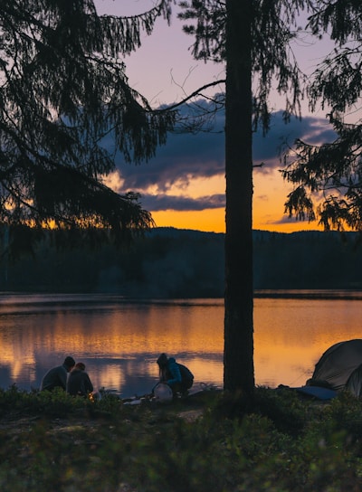 people beside body of water at golden hour