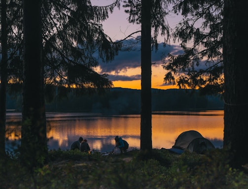 people beside body of water at golden hour