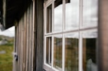 Close-up of natural wood textures and large windows reflecting the surrounding forest.
