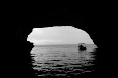 boat on body of water outside the cave