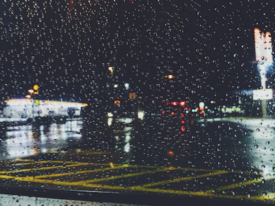 Rain droplets sliding down a large café window overlooking a neon-lit Seattle street.
