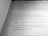 A close-up view of a book page displaying structured code written in a programming language, likely Java. The text is oriented diagonally, capturing sections of code including a method definition and exception handling.