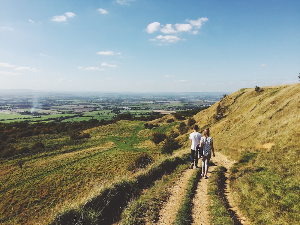 landscape photography of man and woman walking on dirt road