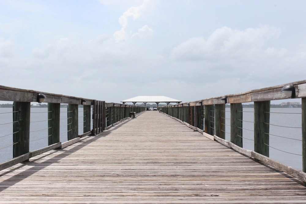 time lapse photography of wooden bridge under cloudy sky