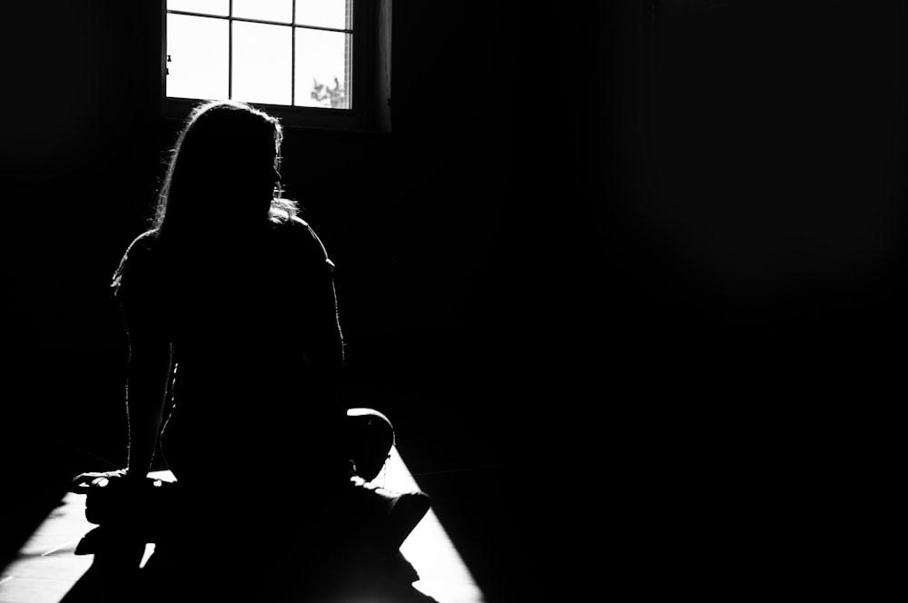 어두운 방에서 바닥에 앉아 있는 여자