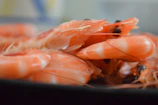 A bowl of bright orange cleaned prawns with a sprinkle of fresh herbs.