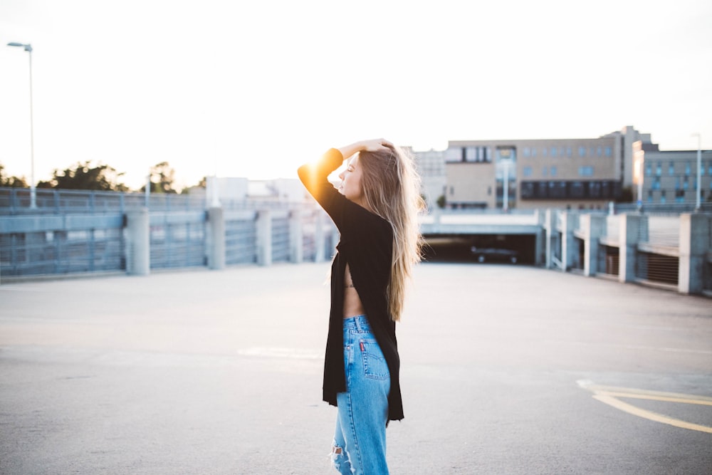 Woman in a long black sweater poses on a parking garage at the University of Arkansas