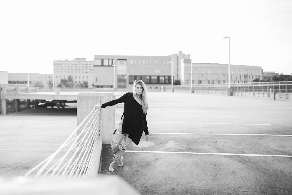 grayscale photo of woman leaning while holding fence