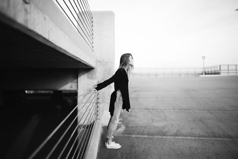 grayscale photography of woman standing near building
