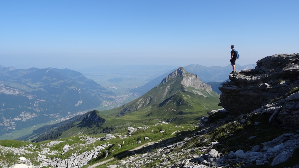 man standing near cliff facing mountains